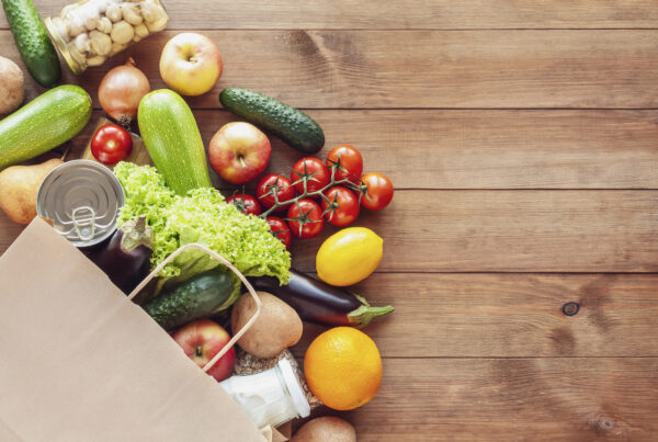 a paper bag filled with fruits and vegetables on a wooden table
