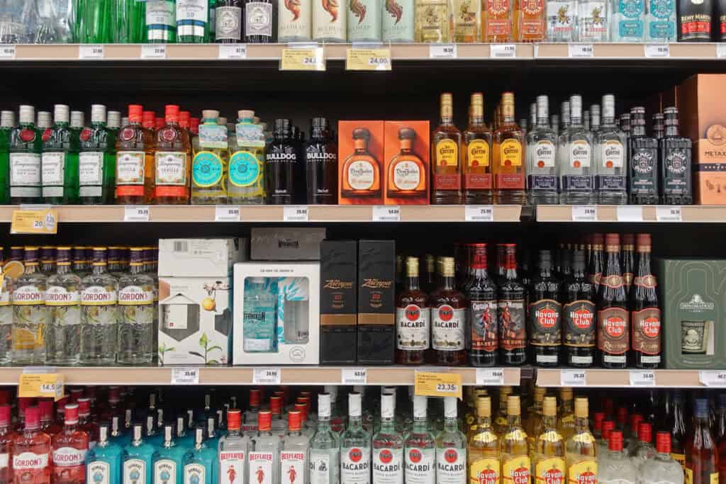 A store shelf full of assorted spirits in bottles and gift boxes on display shelf in a liquor shop.