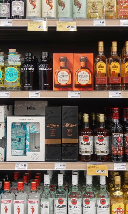 A store shelf full of assorted spirits in bottles and gift boxes on display shelf in a liquor shop.