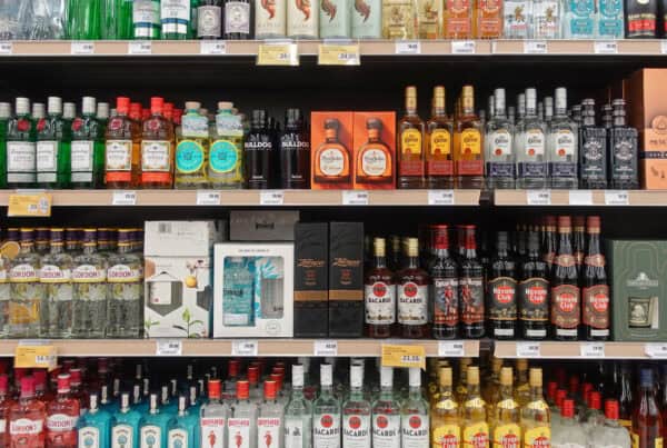 A store shelf full of assorted spirits in bottles and gift boxes on display shelf in a liquor shop.