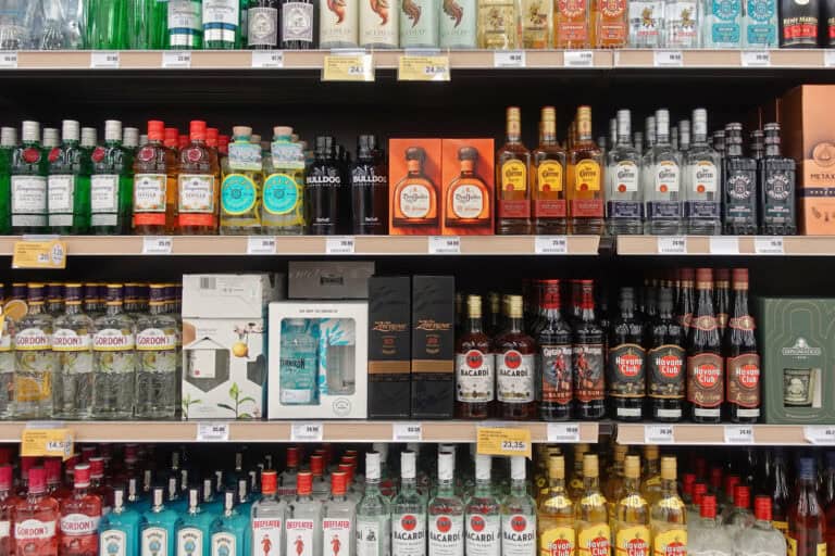 A store shelf full of assorted spirits in bottles and gift boxes on display shelf in a liquor shop.